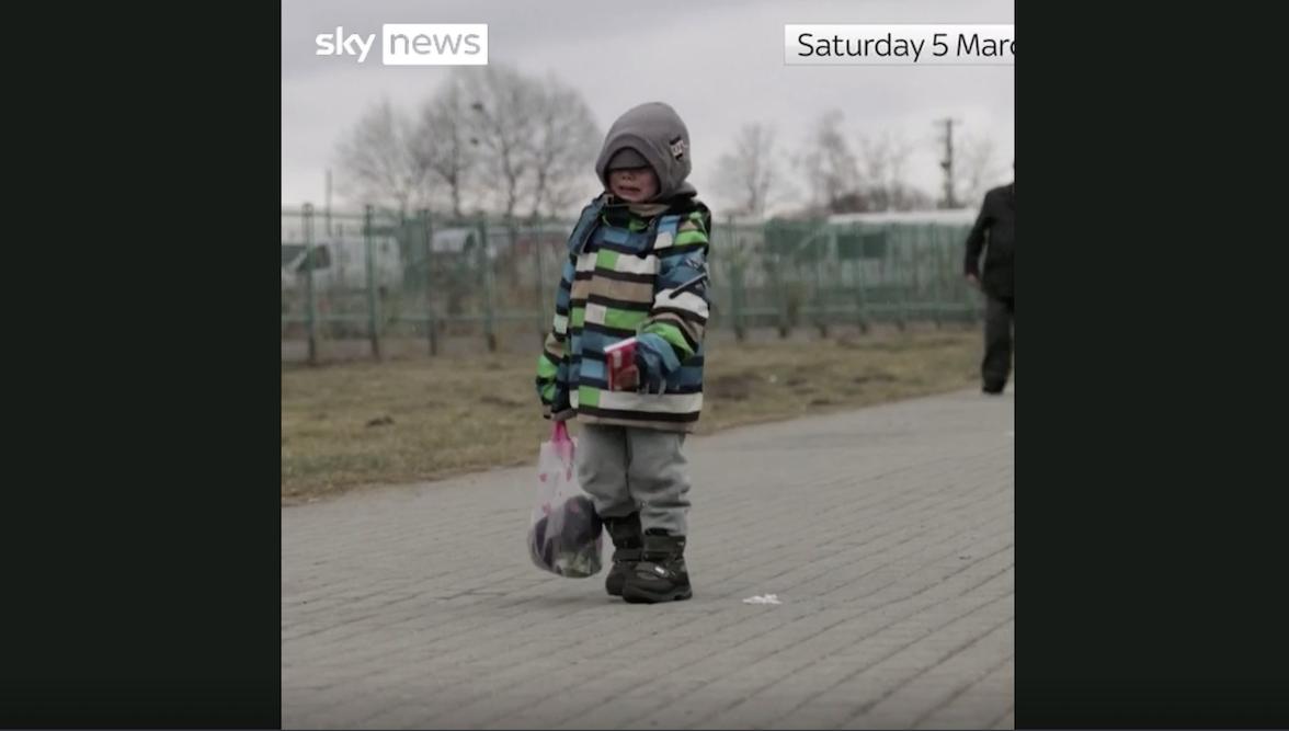 一名烏克蘭男孩哭著獨自走在逃難路上，背著背包，手裡提著玩具。